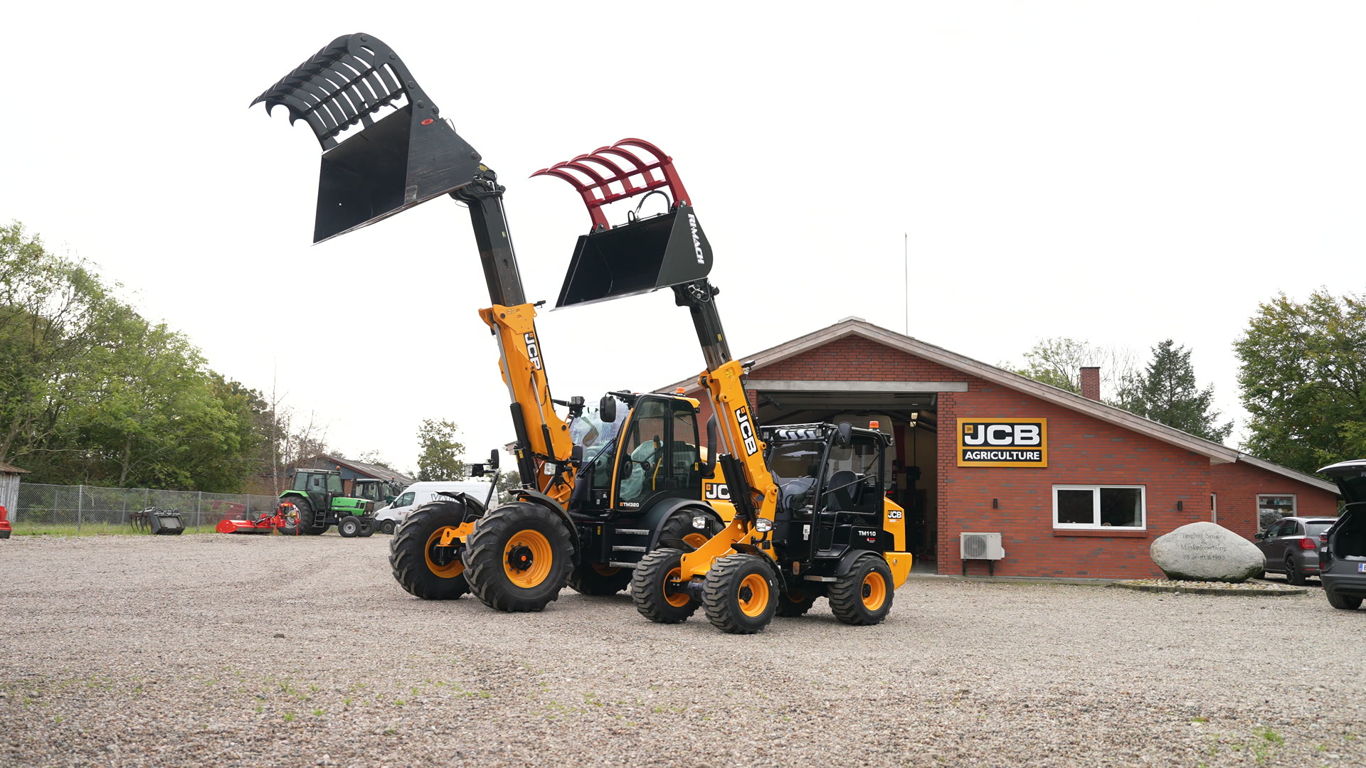 JCB TM320 og TM110 med løftede overfaldsskovle foran Tinghøj Maskinteknik i Varde
